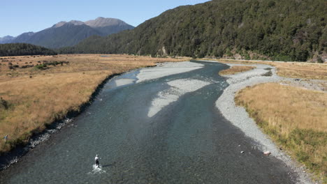Aerial-drone-reveal-pan-up-footage-of-fly-fishing-at-Eglinton-River,-New-Zealand