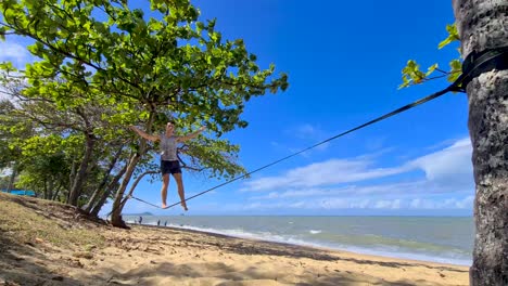 Adult-Male-Getting-On-Slackline-And-Balancing-At-Trinity-Beach-In-Cairns