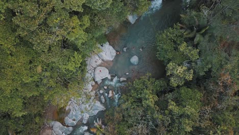 Drohne-Aus-Der-Vogelperspektive-Von-Menschen,-Die-Auf-Einem-Fluss-Inmitten-Eines-Waldes-In-Kolumbien-Schwimmen