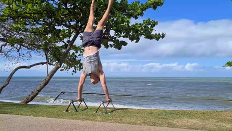 Young-Adult-Male-Practising-Handstand-On-Trinity-Beach,-Cairns