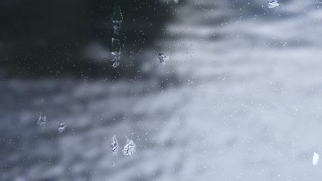 Regentropfen-Auf-Fenstern,-Mit-Einem-Fließenden-Fluss-Verwischen-Den-Hintergrund