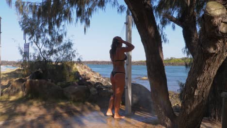 Sexy-Frau,-Die-Einen-Zweiteiligen-Badeanzug-Trägt,-Der-Eine-Dusche-Am-Strand-Nimmt---Duranbah-Beach---New-South-Wales,-Australien