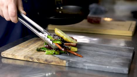Chef-Plating-A-Healthy-Seared-Vegetables-By-Tongs-In-The-Kitchen-Of-A-Restaurant