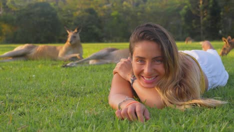 Pretty-Girl-With-Long-Hair-Lying-On-Stomach-On-The-Green-Grass---Girl-Resting-With-Eastern-Grey-Kangaroos---Gold-Coast,-QLD,-Australia
