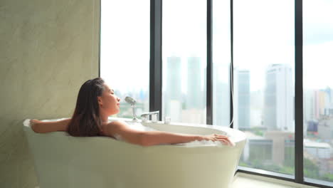 Attractive-Woman-in-Bathroom-Bathtub-Enjoys-City-View-from-High-Floor