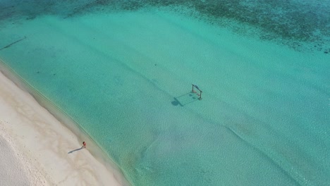 Luftaufnahme-Einer-Einsamen-Frau,-Die-Am-Weißen-Sandstrand-Der-Malediven-insel-Am-Türkisfarbenen-Ozeanwasser-Spazieren-Geht