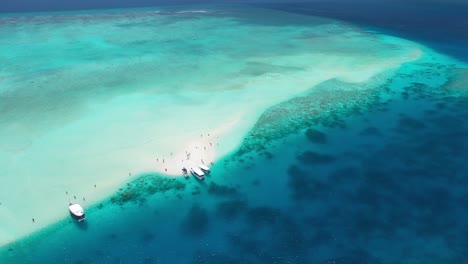 Vista-Aérea-Del-Banco-De-Arena-Tropical-Y-La-Laguna-Con-Arrecifes-De-Coral-Y-Turista,-Maldivas