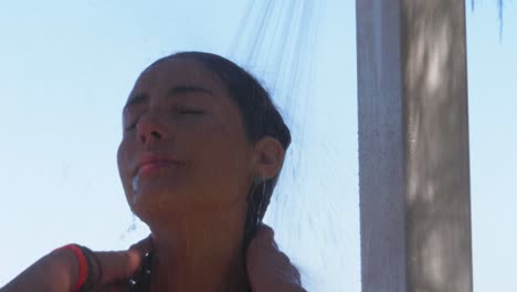 Tanned-Woman-Washing-Face-Under-The-Shower-Then-Smiled-At-The-Camera---Taking-A-Shower-At-Duranbah-Beach-After-Swimming---New-South-Wales,-Australia