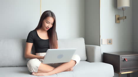 Casual-Young-Woman-Sitting-in-Sofa-at-Home-Using-Laptop-Computer