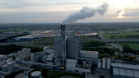 Aerial-of-smoking-factory-chimney-with-an-industrial-area-in-the-background