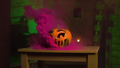 Purple-pink-smoke-coming-out-of-the-pumpkin-in-front-of-green-spooky-background-|-SLOWMOTION