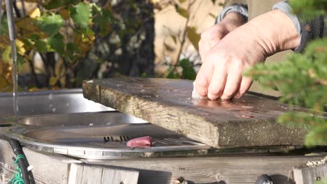 Close-up-of-man-processing-and-slicing-fish-fillet-on-outside-preparation-table