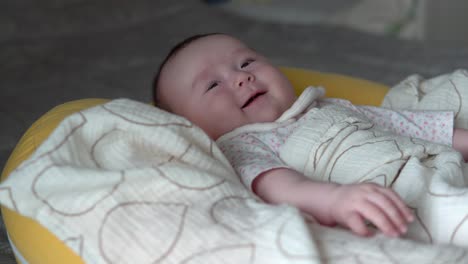 Infant-Baby-girl-Smiling-While-Lying-On-A-Soft-yellow-Cushion