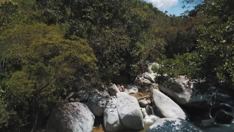 Drohnenluftaufnahme-Eines-Flusses-Im-Wald-Mit-Einem-Wasserfall-Und-Riesigen-Felsen-In-Kolumbien