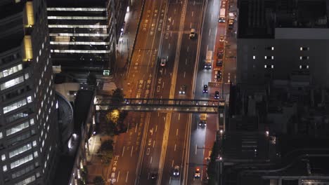Fahrzeuge,-Die-Nachts-In-Tokio,-Japan,-Auf-Der-Shibuya-Straße-Fahren,-Die-Von-Hochhäusern-Umgeben-Ist