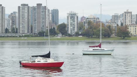 2-Sailboats-dancing-in-the-water,-with-vancouver-skyline-behind