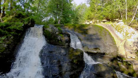 Low-height-waterfall-flowing-through-the-rocks-in-the-middle-of-dense-forest