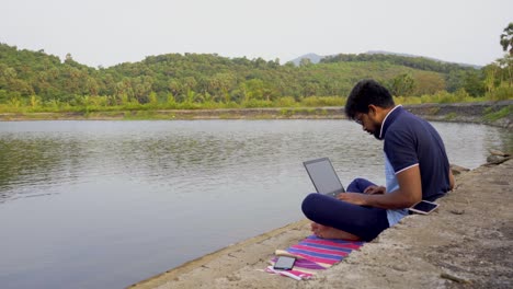 working-remotely-from-a-laptop-without-mask-location-lakeside-India-new-normal-relaxed-enjoying-view