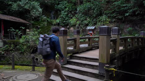 Excursionista-Masculino-Caminando-Sobre-El-Puente-En-Un-Hermoso-Templo-Dentro-Del-Bosque-Oscuro