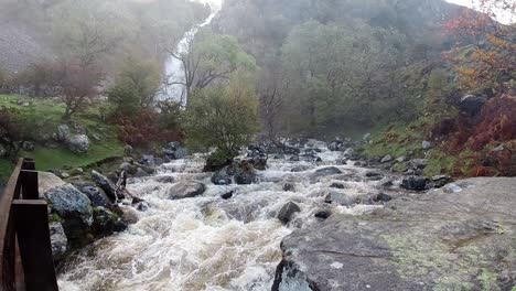 Zeitlupe-Felsiger-Fließender-Wasserfall-Flusswasser-Spritzt-Auf-Neblige-Felsformation-Am-Flussufer