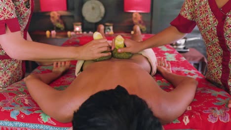 Two-female-spa-therapists-using-herbal-compresses-to-relieve-tension-from-the-back-of-a-woman-enjoying-an-Ayurvedic-spa-treatment