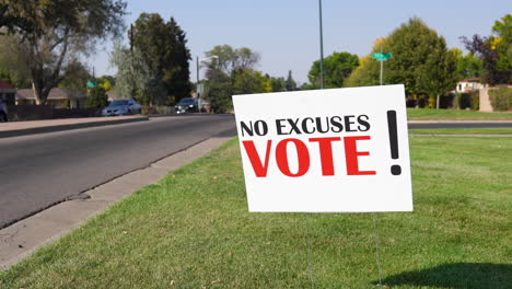 Election-Voter-Rally-Sign-Next-to-Road-with-Cars-Driving-By-Close-Up,-No-Excuses-Vote