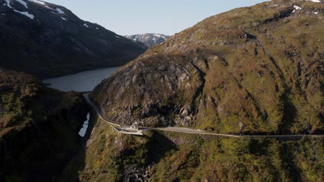 Aerial-View,-Scenic-Norwegian-Landscape,-Hillside-Road-and-Glacial-Lake-on-Sunny-Summer-Day