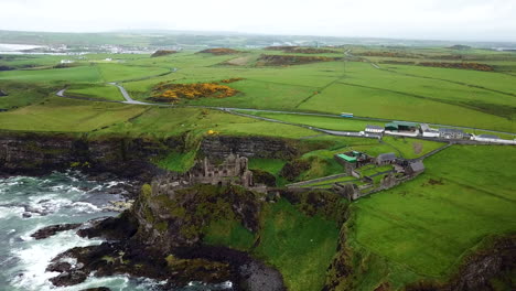 Revealing-drone-shot-of-Dunluce-Castle,-now-ruined-medieval-castle-in-Northern-Ireland
