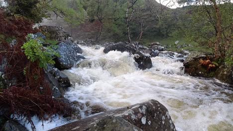 Slow-motion-rocky-flowing-forest-waterfall-river-water-splashing-on-riverbank-rock-formation