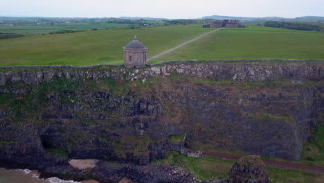 Revealing-drone-shot-of-Mussenden-Temple-located-on-cliffs-near-Castlerock-in-County-Londonderry,-in-Northern-Ireland