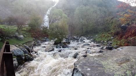 Slow-motion-rocky-flowing-waterfall-river-water-splashing-on-forest-riverbank-rock-formation