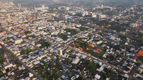 AERIAL:-Drone-Panning-Down-high-above-a-Buddhist-Temple-surrounded-by-Densely-Populated-Nakhon-Ratchasima-Town-in-Korat-Province,-Thailand