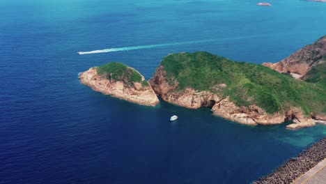 Aerial-tracking-view-boat-sailing-off-the-coast-of-lush-tropical-Sai-Kung-island-landscape-Hong-Kong