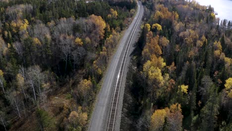 A-slow-aerial-dolly-forward-over-train-tracks-running-through-idyllic-autumn-boreal-forest-in-the-Canadian-shield