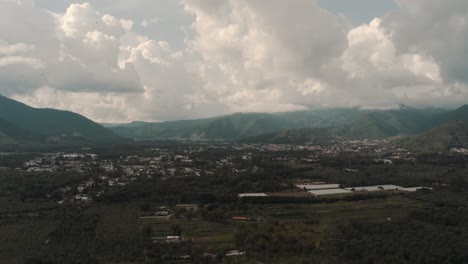 Drone-aerial-landscape,-green-scenery,-clouds-and-mountains,-shot-during-a-beautiful-day-in-Guatemala