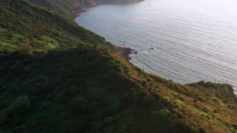 Luftaufnahme-über-Den-üppig-Grünen,-Tropischen-Berggipfel-Der-Insel-Lantau-Mit-Blick-Auf-Die-Plätschernden-Wellen-Des-Ozeans