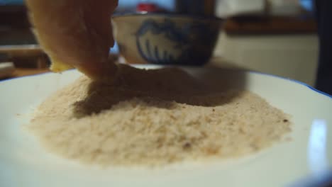 Hand-dips-schnitzel-meat-in-flour-bowl-for-cooking,-close-up