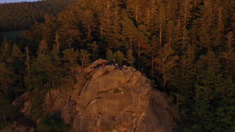 Gruppe-Von-Teenagern-Auf-Felsvorsprung-Und-Klippe-Eines-Riesigen-Gebirges,-Während-Die-Drohne-Rückwärts-Fliegt-Und-Die-Ganze-Bergkette-Im-Schwarzwald,-Deutschland,-In-4k-Enthüllt