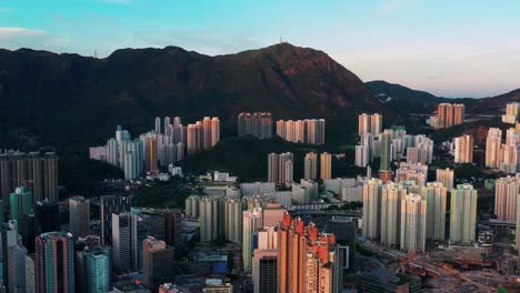 Colourful-sunrise-coloured-aerial-view-above-Kowloon-city-high-rise-towers-and-mountain-peak-skyline-Hong-Kong
