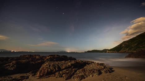 Busy-Lantau-island-lights-moving-across-coastline-horizon-under-tranquil-cloud-forming-starry-night-sky