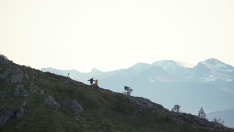 Zwei-Personen-Gehen-Einen-Steilen-Hügel-Hinunter,-Umgeben-Von-Nebel-Und-Bergen