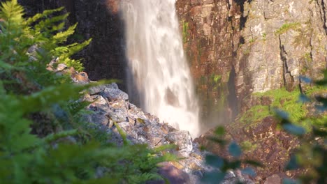 Low-angle-Medium-long-shot-of-base-of-rocky-Njupeskär-waterfall,-plunging-fresh-water-between-eroded-canyon,-at-Fulufjället-National-Park,-in-Särna,-Sweden
