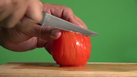 Hands-cutting-a-red-tomato-on-a-chroma-background