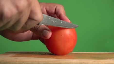 Hands-slicing-through-a-tomado-with-a-knife-on-a-chroma-background