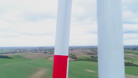 Not-Spinning-White-And-Red-Painted-Windmill-With-Greenfield-And-Cloudy-Sky-Background-In-Kwidzyn,-Poland---Closeup-Shot
