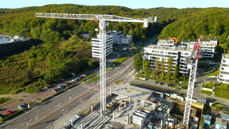 Two-Flat-Top-Tower-Cranes-In-A-Construction-Project-In-Gdynia,-Poland---descending-drone-shot