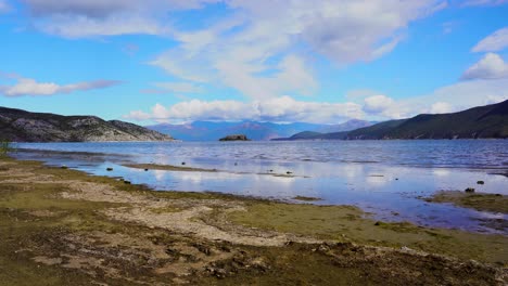 Tranquilo-Lago-De-Prespa-En-Otoño-Con-Costa-Seca-Y-Aguas-Tranquilas-Que-Reflejan-Nubes-Blancas-En-El-Cielo-Azul