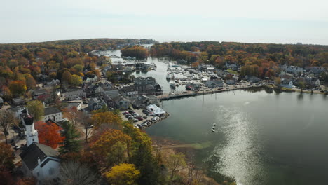 Autumn-aerial-scenery,-calm-river-across-busy-town-center-with-harbor,-Kennebunkport-Maine