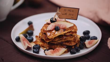 Mothers-Day-Pancakes-WIth-Pink-Rose-Served-On-The-Wooden-Table---A-Plate-Of-Pancakes-With-Blueberries-And-Maple-Syrup