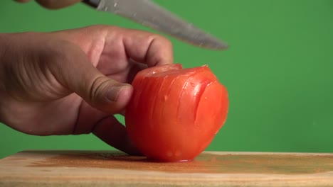 Hands-cutting-in-slices-a-tomato-on-a-chroma-background